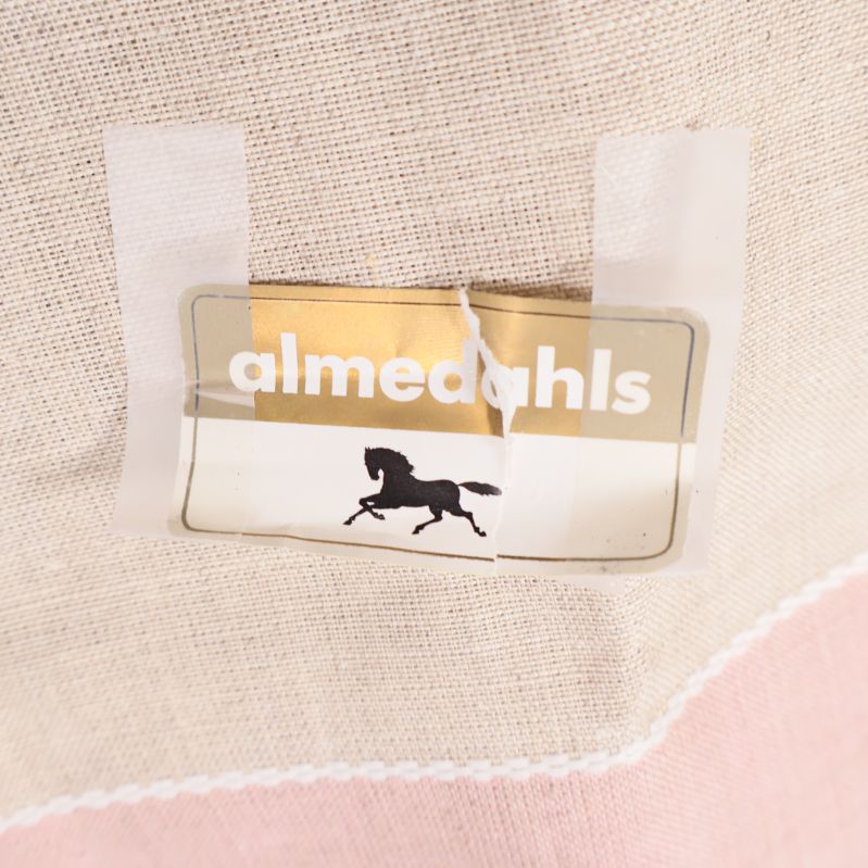 Etikett med almedahls logga och hästmotiv på textil