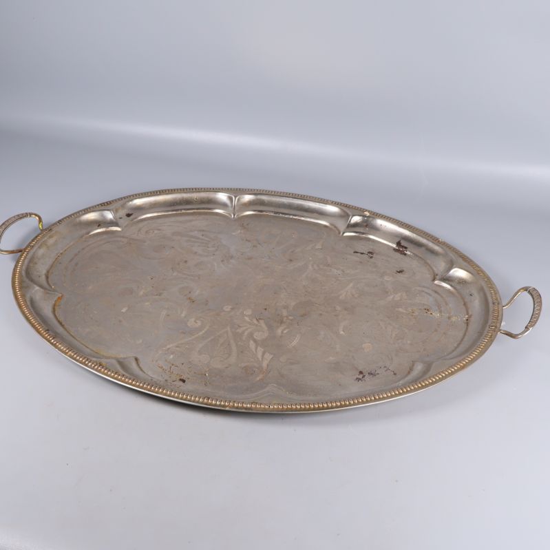 Oval serveringsbricka i metall med graverat mönster och handtag