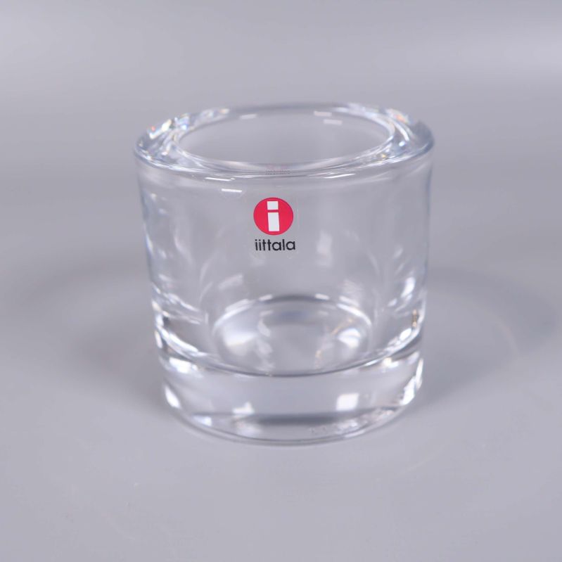 En ljushållare i glas med rött Iittala-klistermärke
