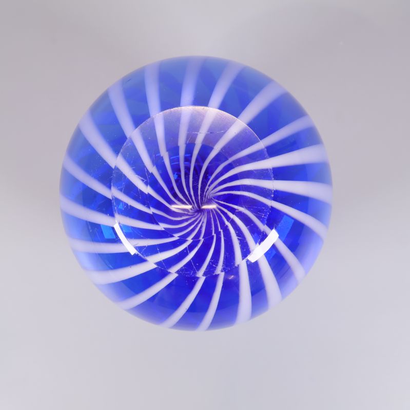 Undersida av blå vas med vitt spiralformat mönster