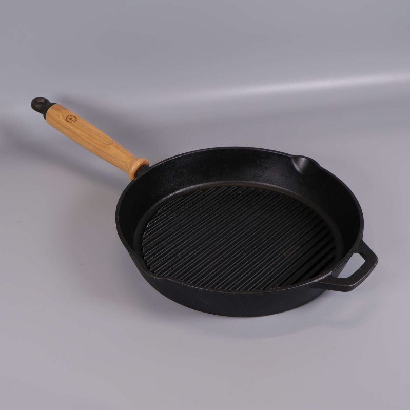 Svart grillpanna med trähandtag fotad snett uppifrån