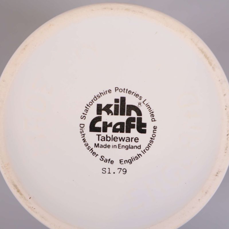 Närbild av Kiln Craft logotyp och tillverkningsinfo under muggen
