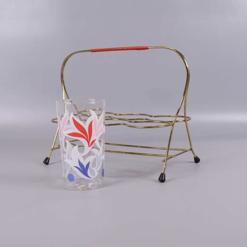 Ett glas och tomt metallställ uppställda bredvid varandra
