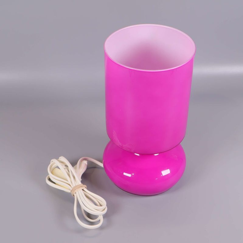 Rosa bordslampa med vit sladd sedd snett framifrån