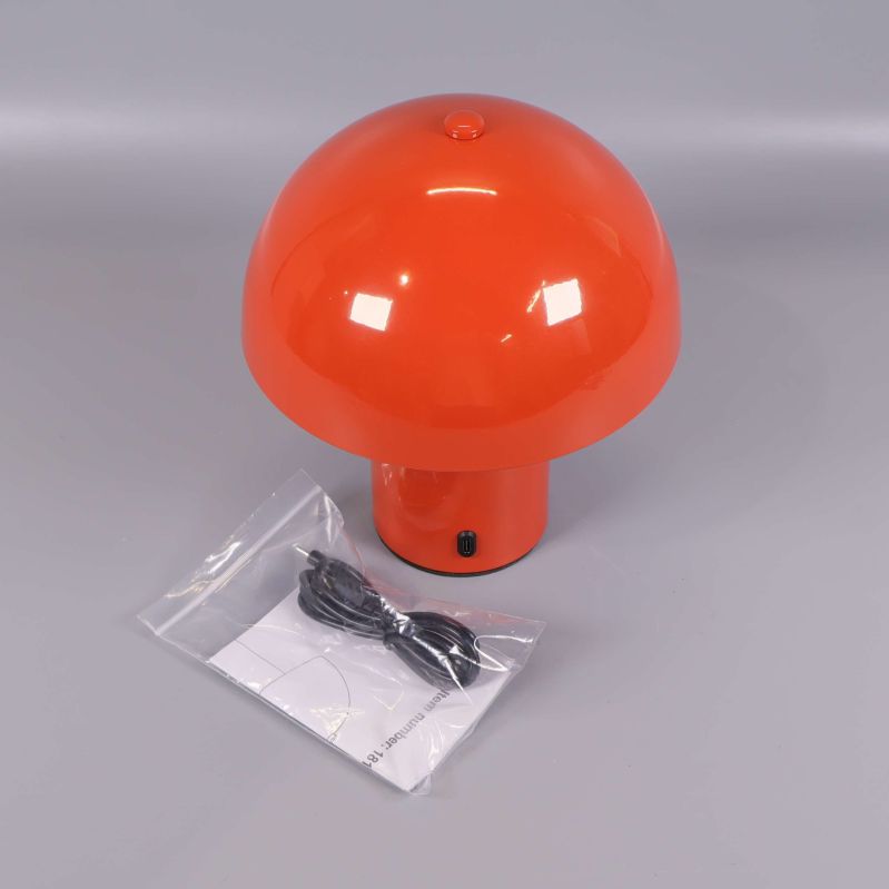 Orange svampformad bordslampa med laddkabel i påse bredvid