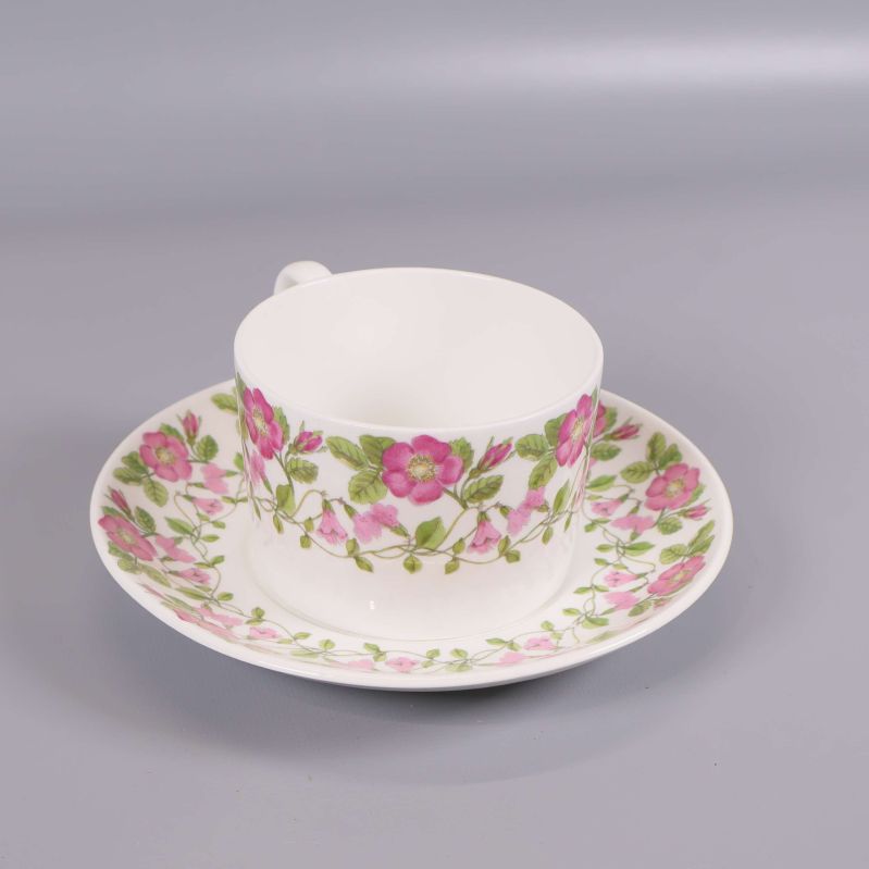 Tekopp med fat dekorerad med rosa blommor