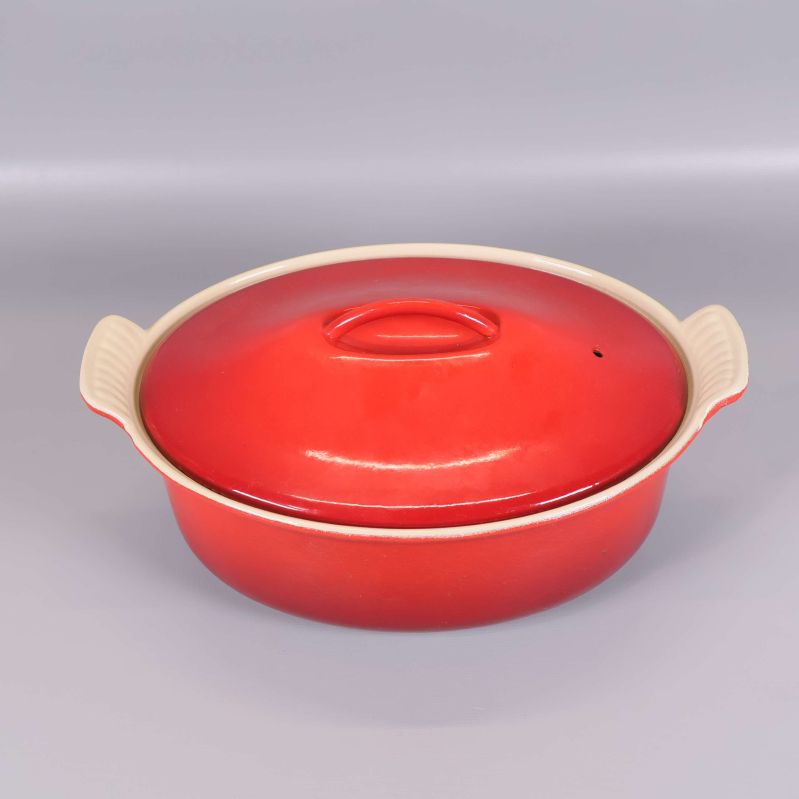 Röd oval gryta med lock och handtag
