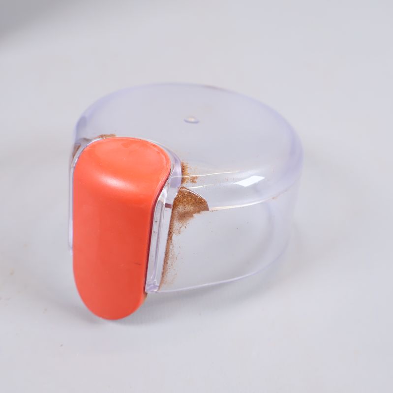 Avtagbart transparent lock med orange tryckknapp och kafferester
