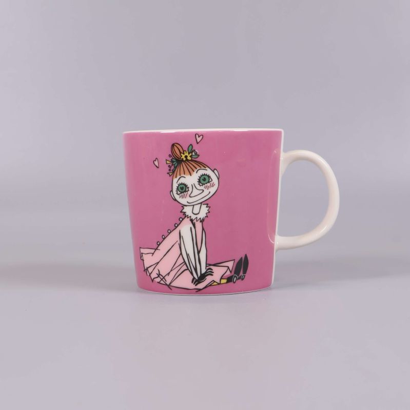 Sida av mugg med sittande Muminfigur på rosa bakgrund