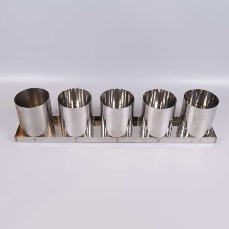 Fem cylinderformade metall brödformar i rad på en bricka