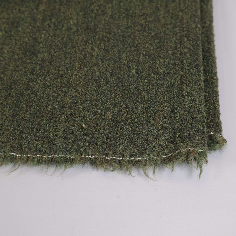 Närbild på fransig tygkant i mörkgrönt material