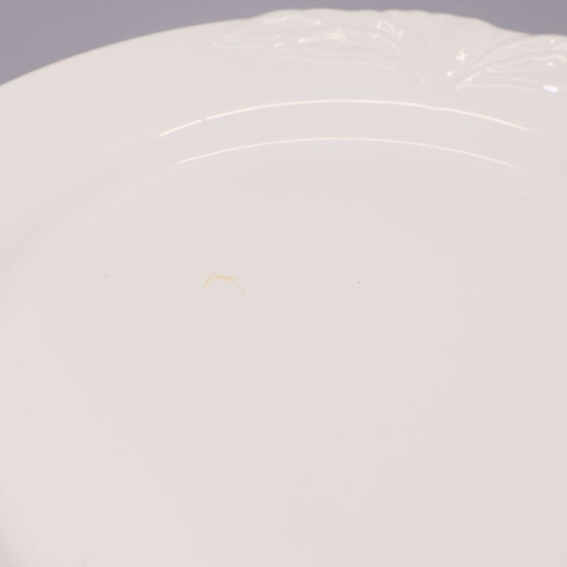 Närbild på reliefdekor och mindre fläck på vit assiett
