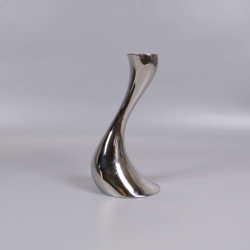 Böjd ljusstake i blank metall på ljus bakgrund