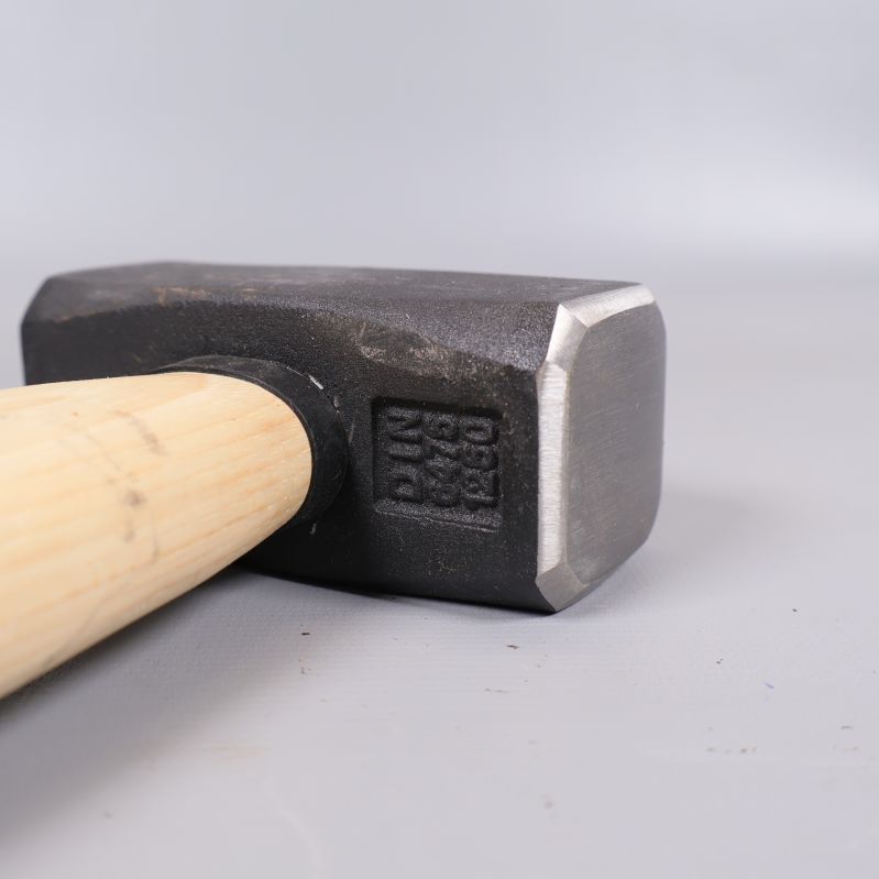 Närbild på släggans metallhuvud och gravering