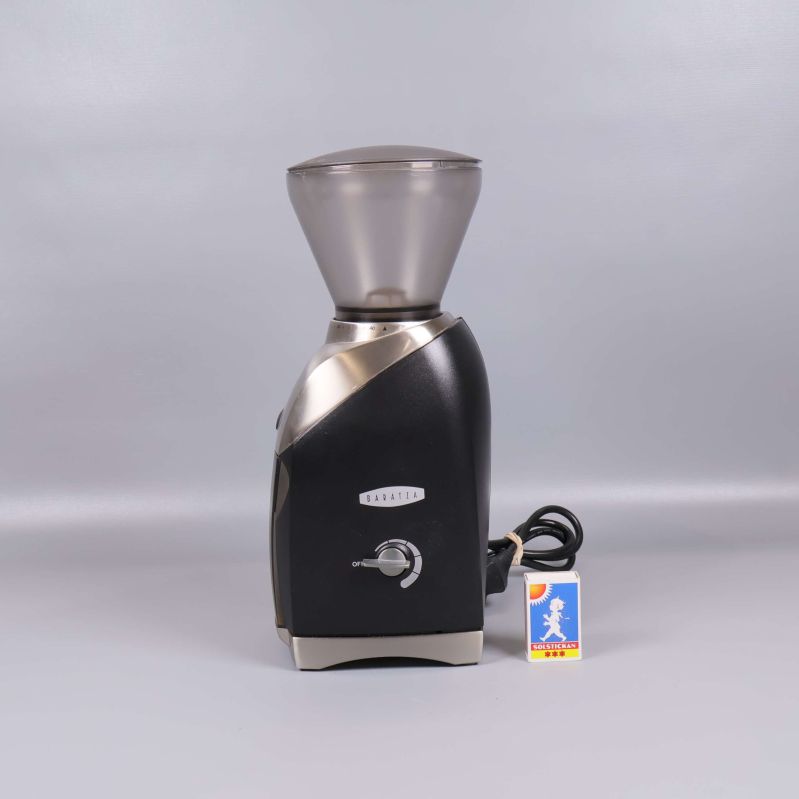 Kaffekvarn i svart och metall sedd från sidan med sladd