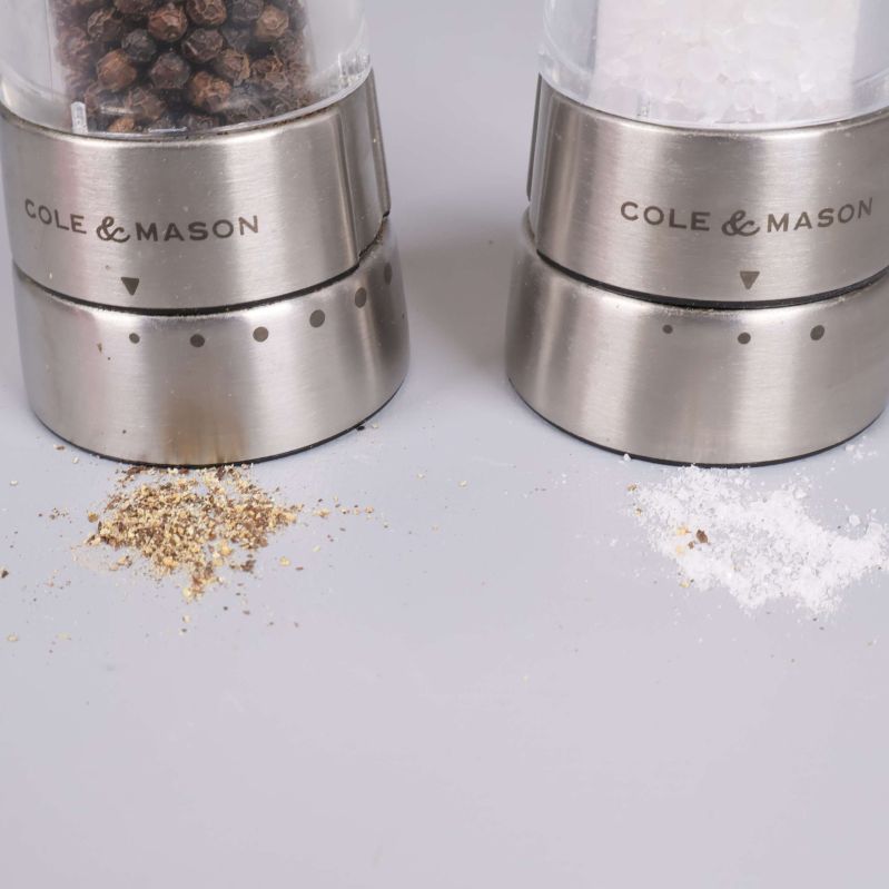 Närbild på kvarnarnas nederdel och spilld salt samt peppar
