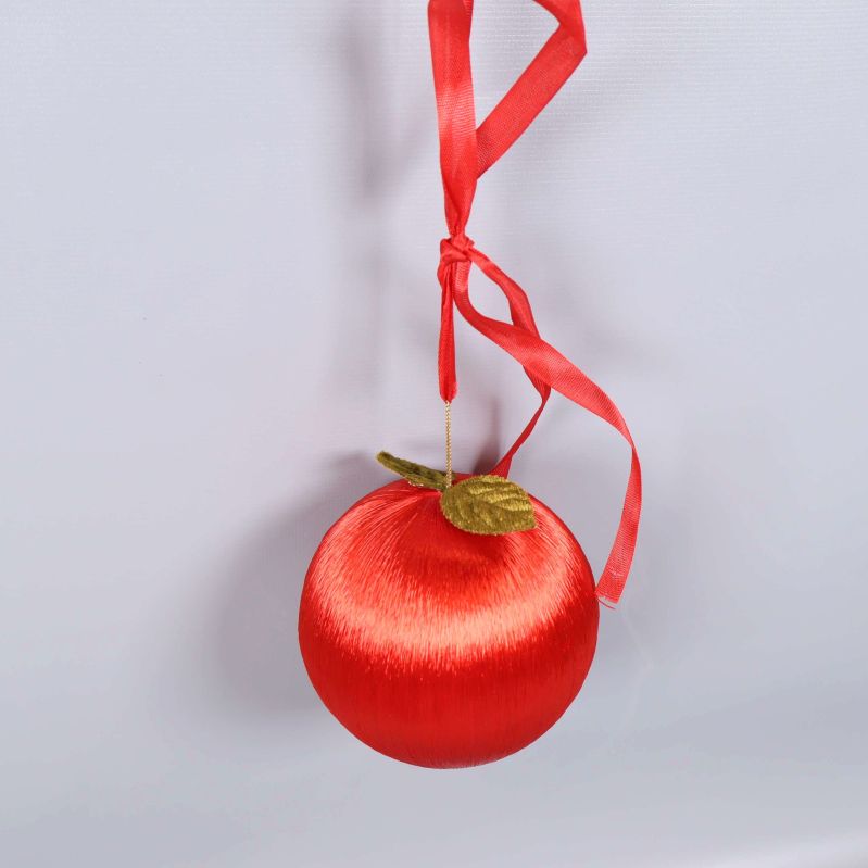 Rött äpple med grönt blad och rött band i närbild