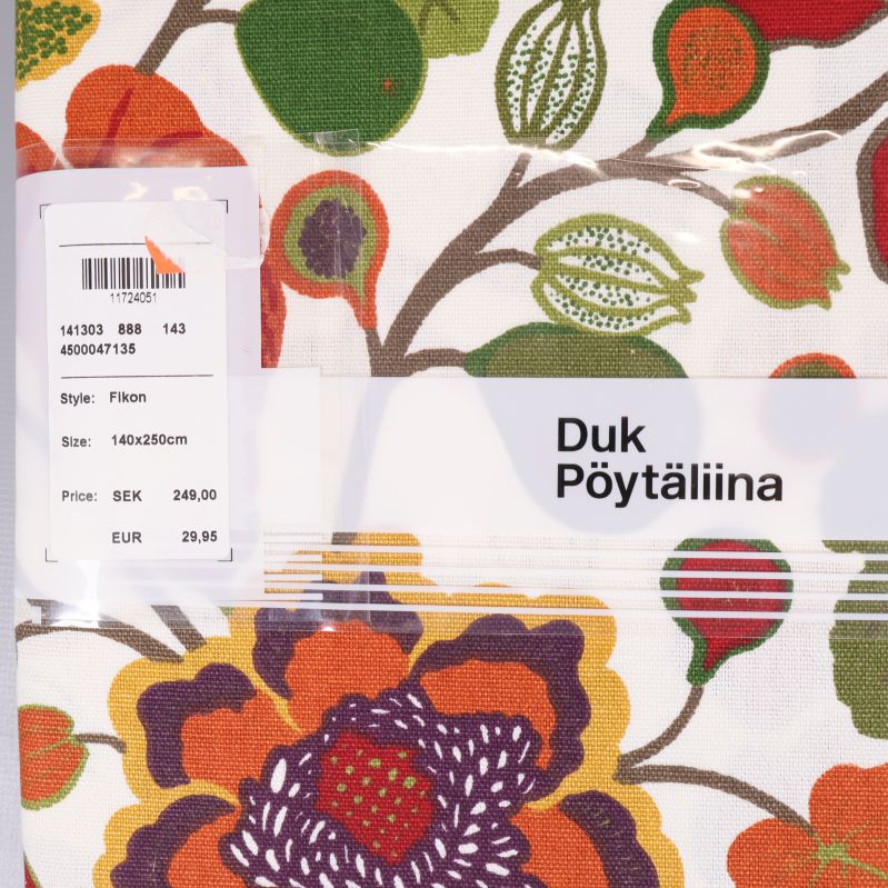 Närbild på vit duk med färgstarkt blommönster och etikett