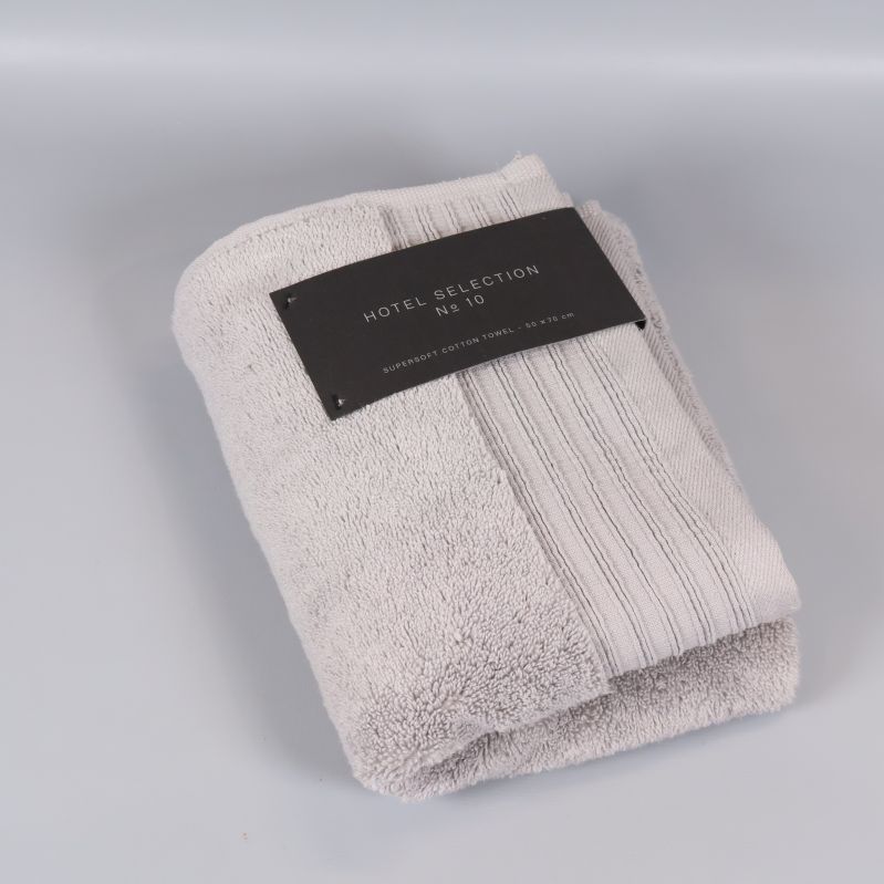 Gråvit handduk viks med textiletikett ovanpå