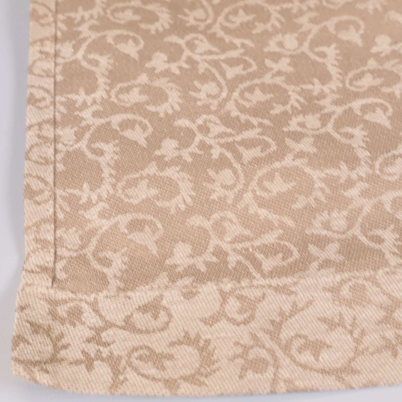 Hörndetalj av mönstrad beige bordslöpare med sydd kant