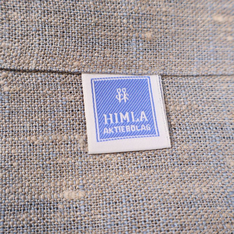 Närbild av textilämärke med blå HIMLA AKTIEBOLAG på servetten