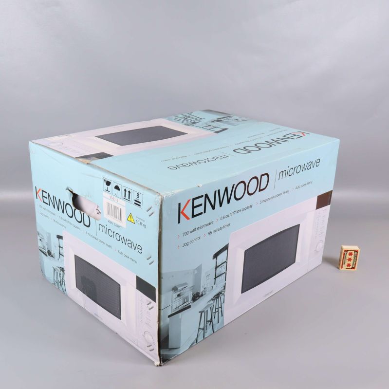 Kenwood mikrovågsugn i kartong fotad snett bakifrån
