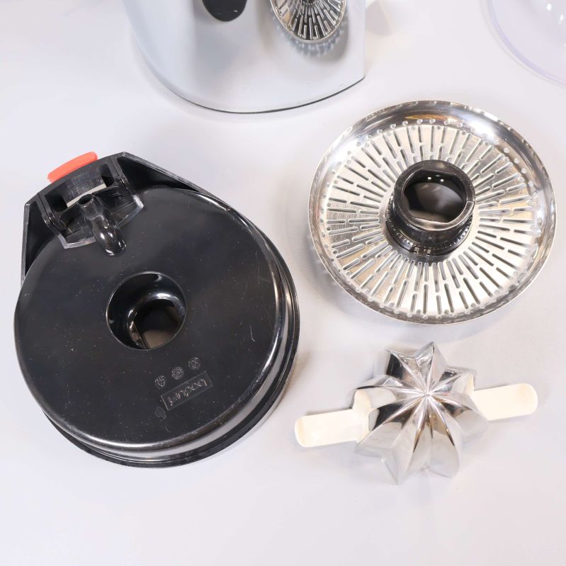 Närbild på olika citruspressens metalldelar och lock