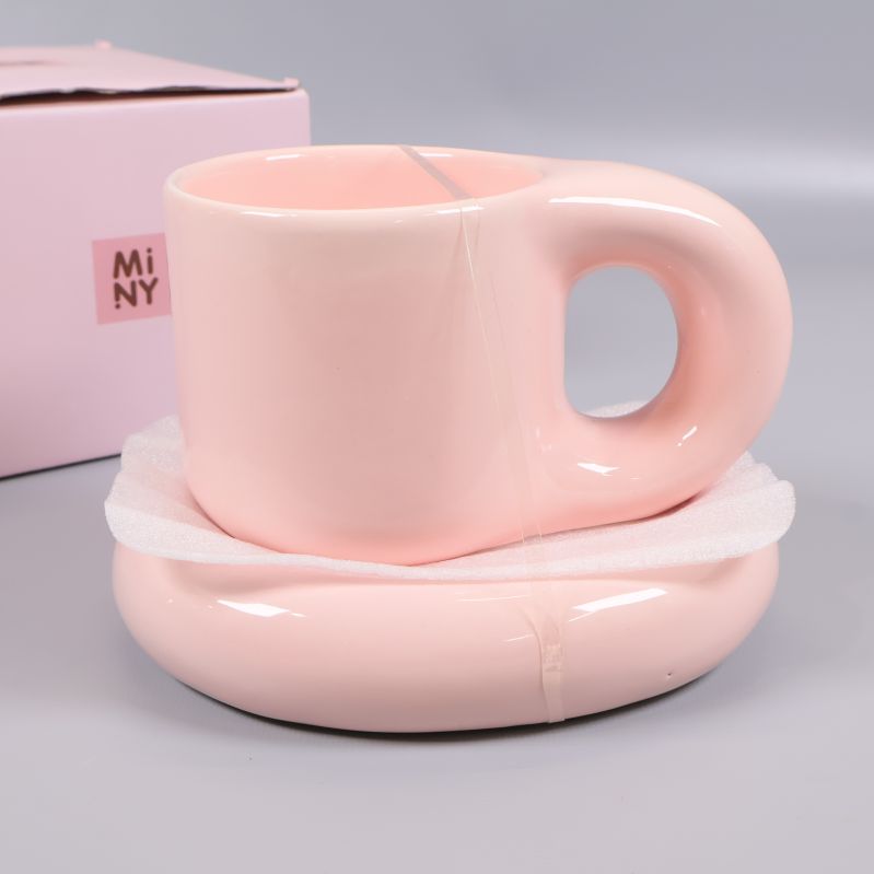 Närbild på pastellrosa mugg och fat