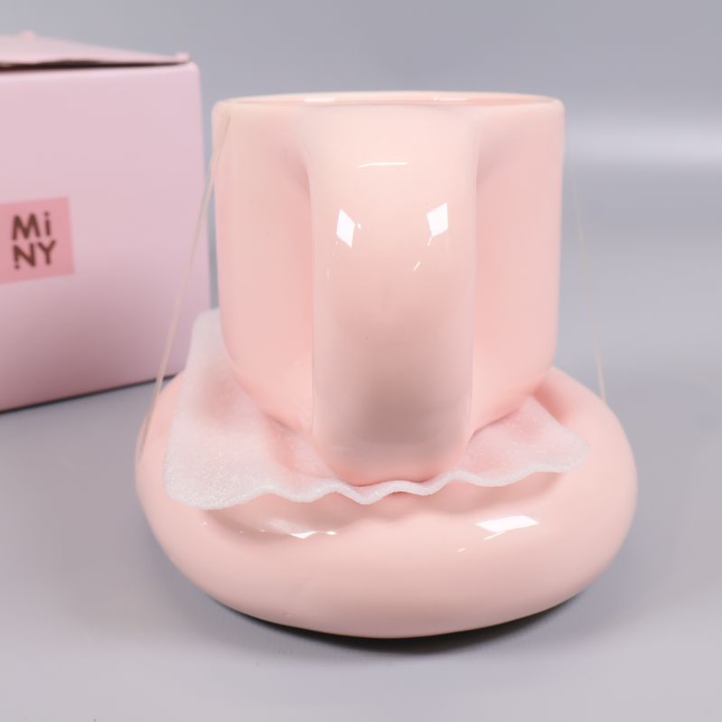 Baksida på pastellrosa mugg ovanpå fat