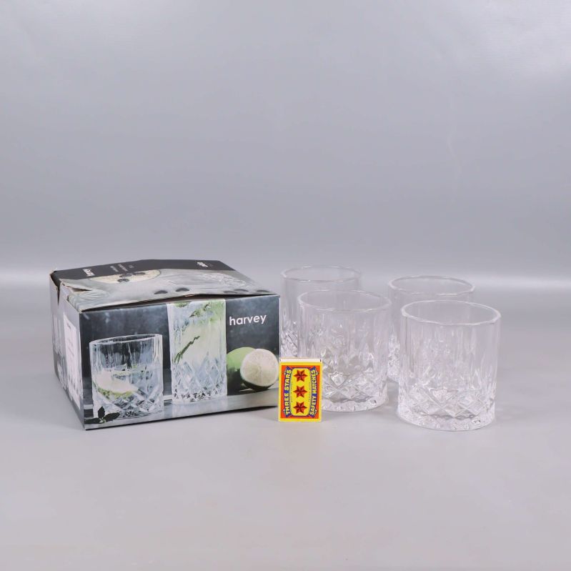 Fyra whiskyglas, originalförpackning och en tändsticksask på grå bakgrund