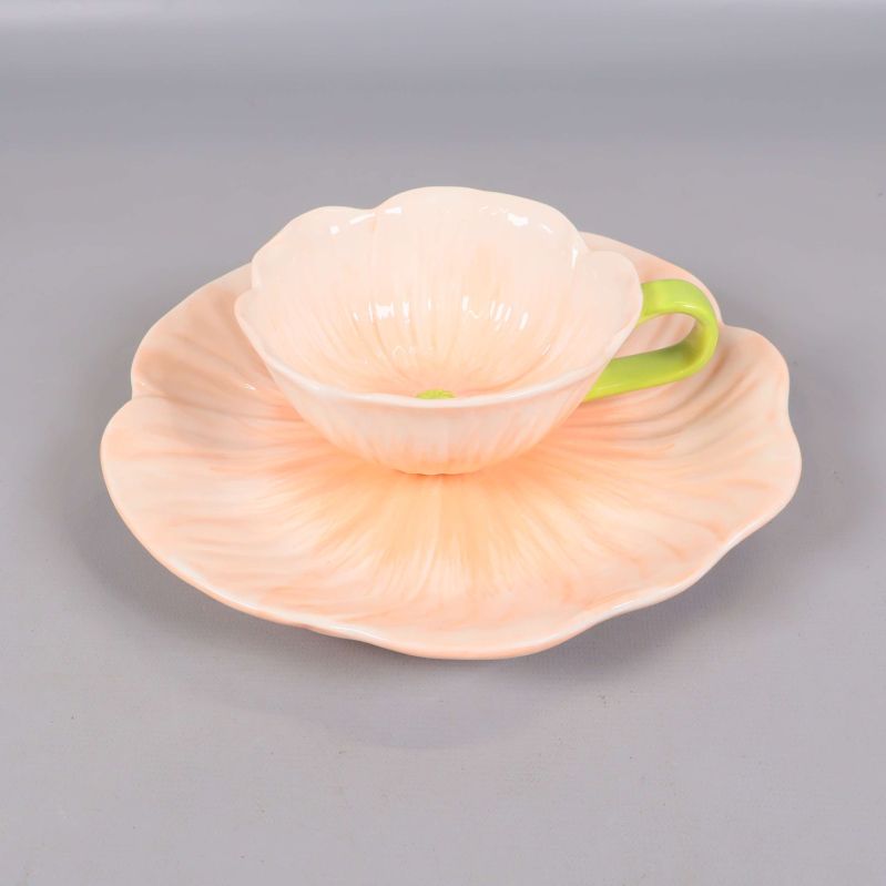 Närbild på blomformad kopp och fat med grönt handtag