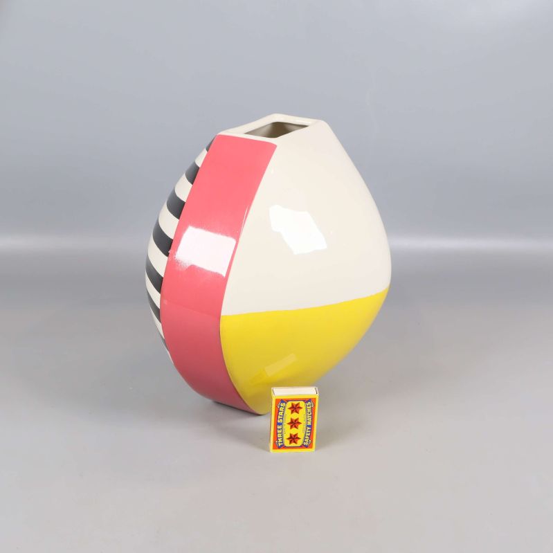 Randig vas med gul, rosa och svartvit design med tändsticksask bredvid