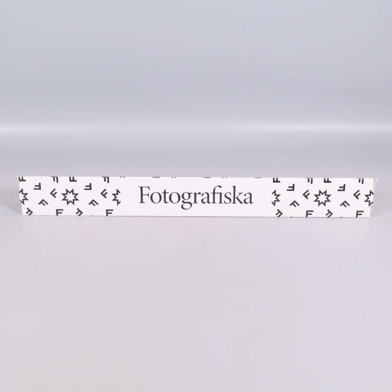 Vit kartong med svarta mönster och texten Fotografiska