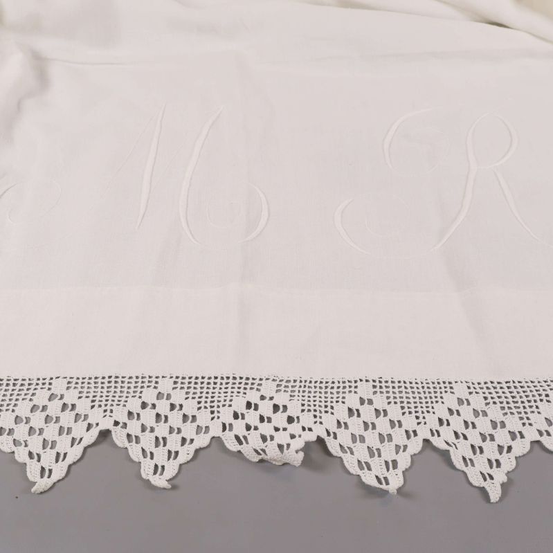 Närbild på broderade initialer och spetsdetalj