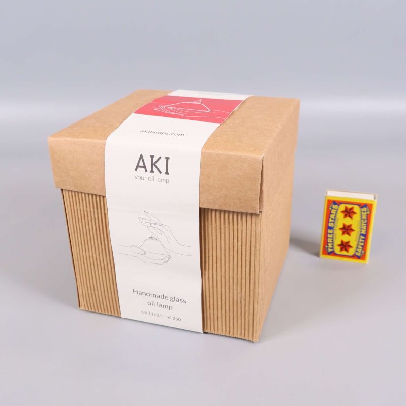 Stängd kartong med AKI oljelampa och tändsticksask intill