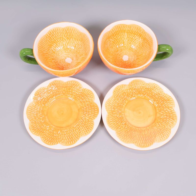 Uppifrån syn på två koppar och två fat med orange detaljmönster