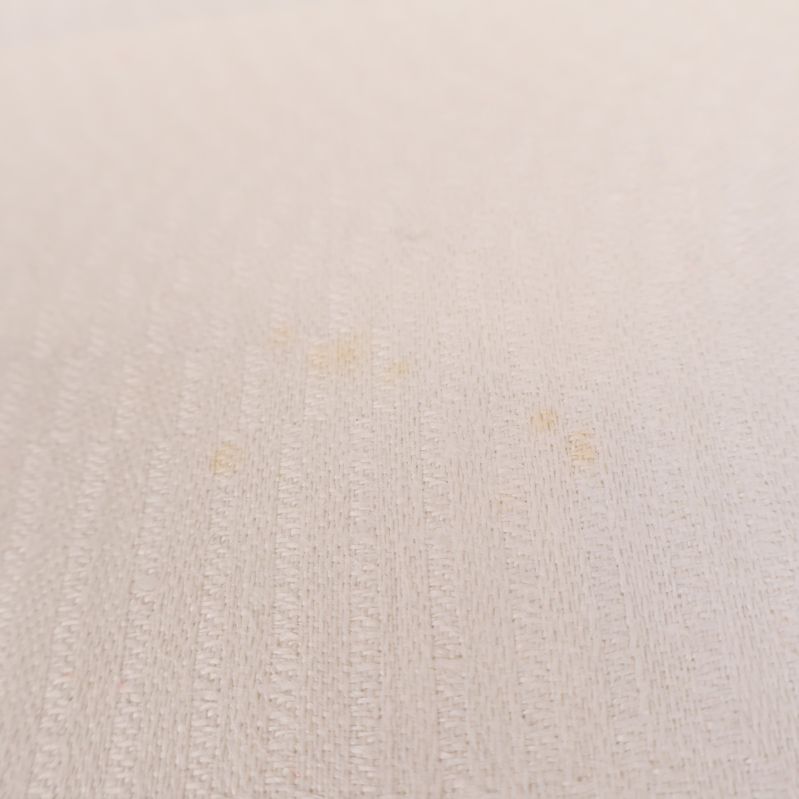 Närbild av små fläckar på vit textil