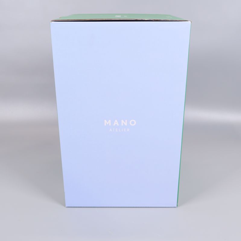 Ljusblå sida av kartong med logga Mano Atelier