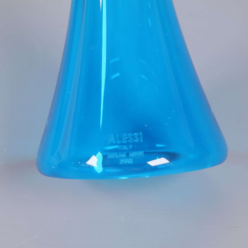 Närbild av Alessi-logotypen på blå glasskålens fot