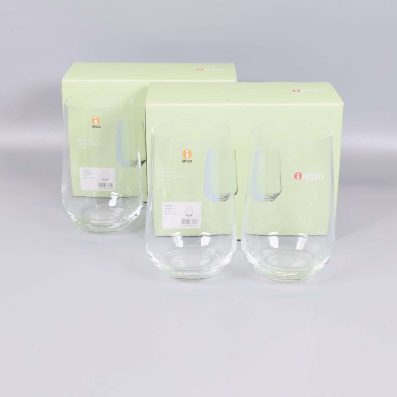 Fyra Iittala Tumbler-glas framför ljusgröna förpackningar