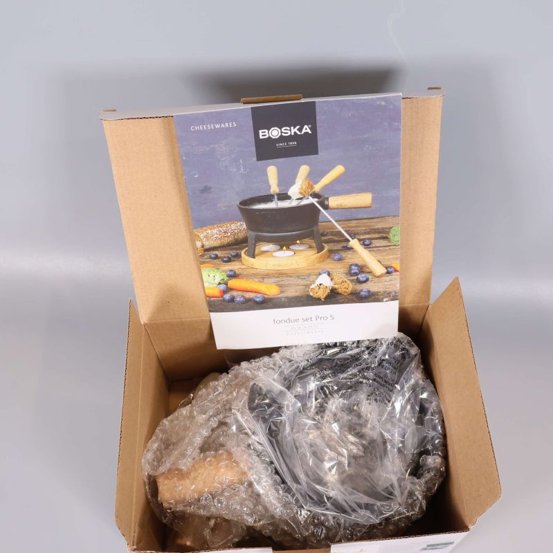 Öppen kartong med Boska fondue-set delvis i bubbelplast