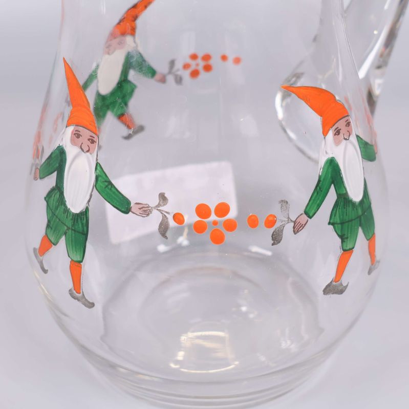 Närbild på tomte och orange dekoration på glaskanna