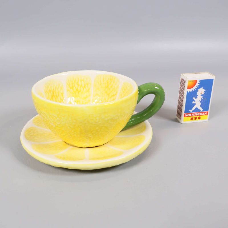Citronmönstrad kopp med fat och tändsticksask bredvid