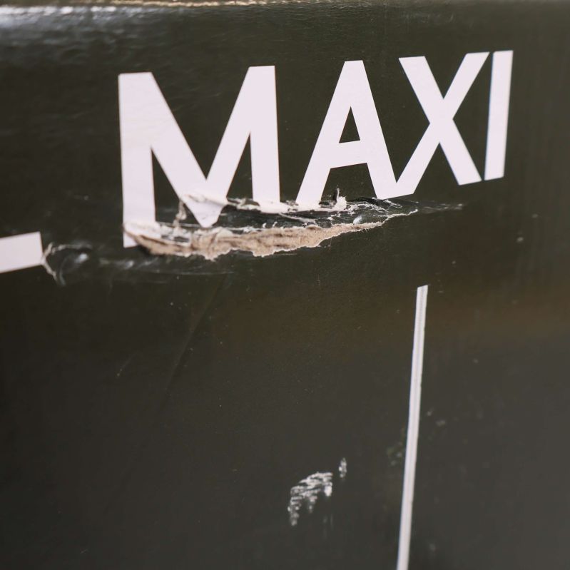 Närbild på skada i kartongens ovansida vid texten Maxi