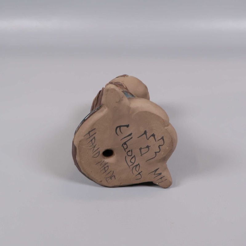 Keramikfigurens undersida med signering och text Hand Made