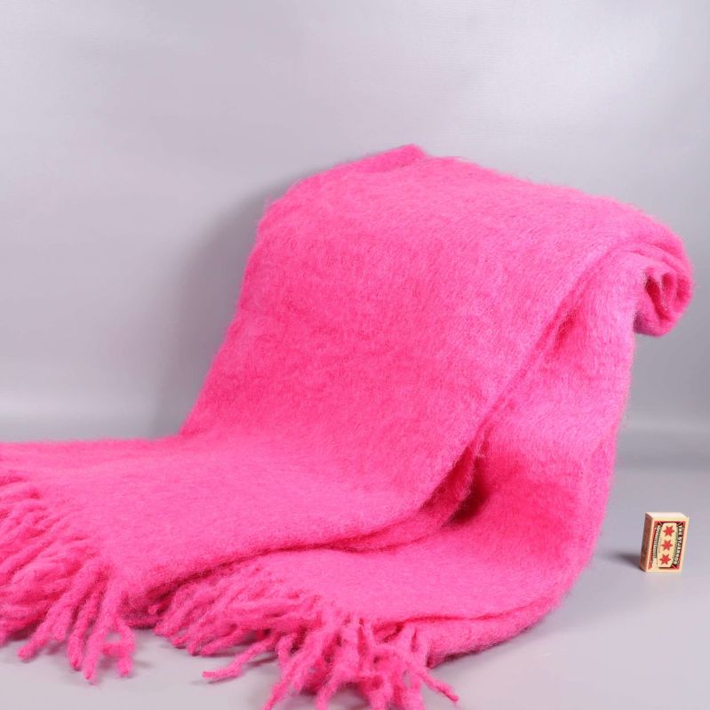 Rosa mohairpläd utbredd med tändsticksask bredvid