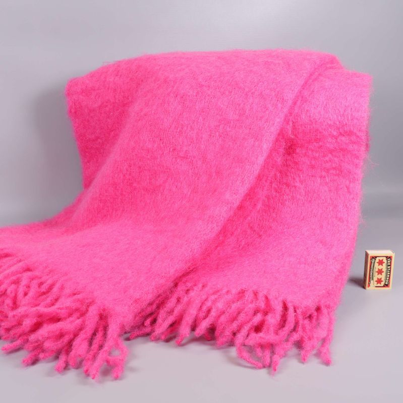 Utbredd rosa mohairpläd med fransar och tändsticksask