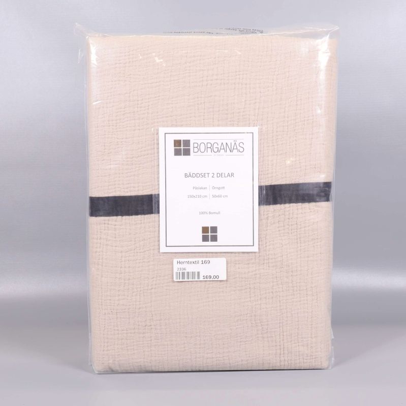 Oöppnat bäddset i beige med mörk rand och etikett
