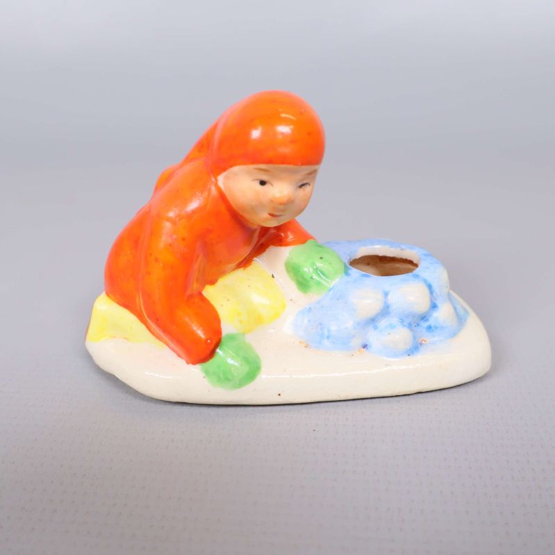 Närbild på figur i orange och grönt vid ljushållare