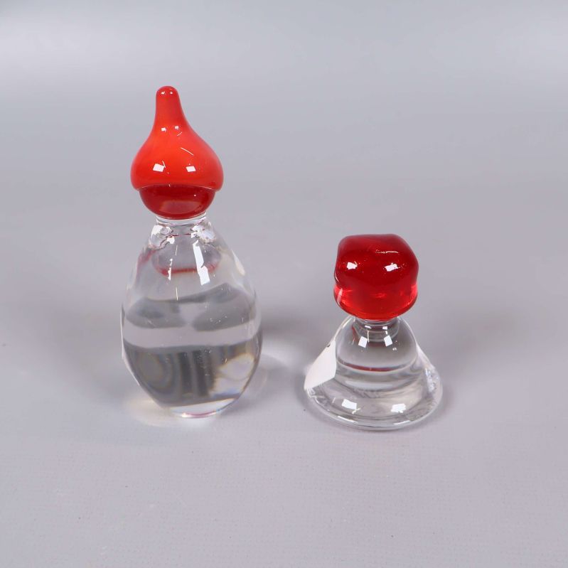 Två glasfigurer med röda luvor på rad